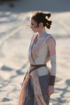 a woman in a star wars costume is standing on the beach with her hands behind her back