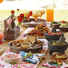 a table topped with plates and bowls filled with food next to glasses of orange juice