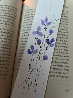 an open book with watercolors on it and a purple flower in the middle