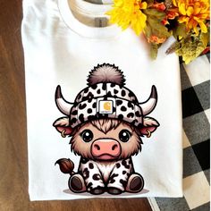 a white shirt with a cow wearing a hat on it's head and flowers in the background