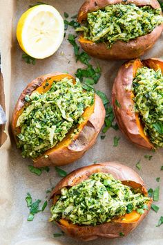 baked sweet potatoes with pesto and lemon wedges on parchment paper in wooden tray