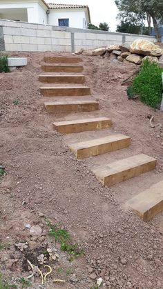 there is a set of wooden stairs going up the side of a hill in front of a house