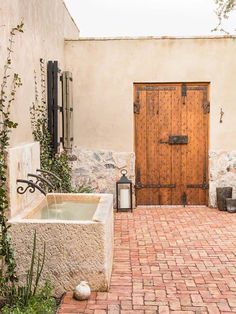 an outdoor jacuzzi tub in front of a door and brick patio with potted plants