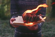 a person holding an open book with flames coming out of it