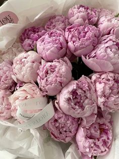 a bouquet of pink peonies is wrapped in white paper and labeled with the word love