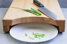 a knife and some green onions on a white plate