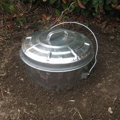 a round metal container sitting in the dirt