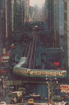 an elevated train on tracks in the middle of a city with tall buildings and traffic