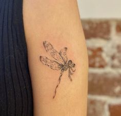 a small dragonfly tattoo on the arm