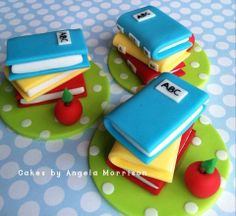 there are three cakes made to look like books and apple on the plate with polka dots