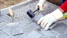 a person with gloves on is using a trowel to put cement in the ground