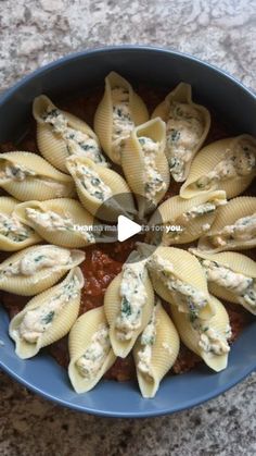 a blue bowl filled with pasta shells covered in sauce