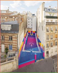 an aerial view of a basketball court in the middle of buildings with colorful paint on it