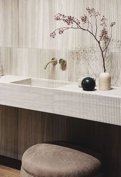 a bathroom with two sinks and a stool in front of the sink, along with a vase