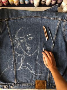 someone is drawing on a jean jacket with crayons and pencils in front of them