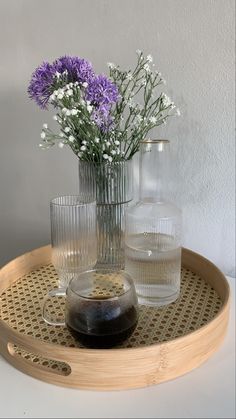 three vases with flowers in them sitting on a tray next to glasses and a pitcher