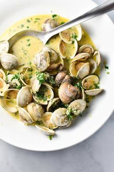 clams in herb butter broth on a white plate with text overlay that reads clams in herb butter broth