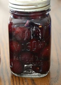 a mason jar filled with fresh strawberries on top of a wooden table