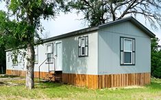 a mobile home sits next to a tree