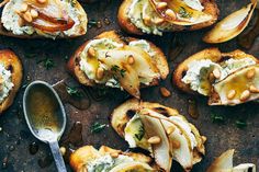 toasted bread topped with pears and whipped cream on a baking sheet next to a spoon