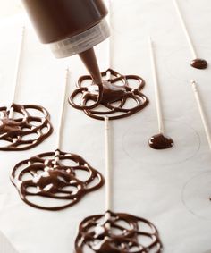 chocolate icing being piped onto marshmallows on a white tablecloth