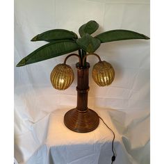 a lamp that is sitting on top of a white table cloth with a green plant in it