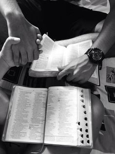 two people holding hands over an open book