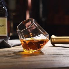 a glass filled with liquid sitting on top of a wooden table