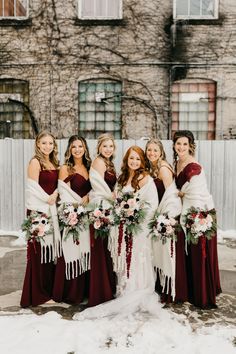 a group of women standing next to each other in front of a building with snow on the ground