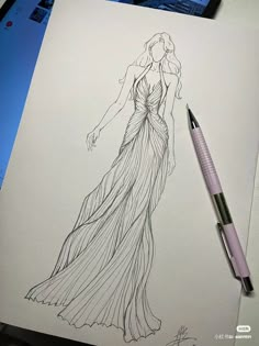 a drawing of a woman's dress on paper with a pen next to it