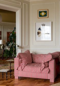 a red and white striped couch sitting on top of a hard wood floor