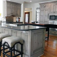 a large kitchen with wooden floors and gray cabinets