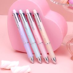 three pens sitting next to each other on a pink surface