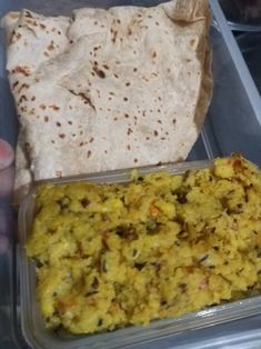 a plastic container filled with food next to a tortilla