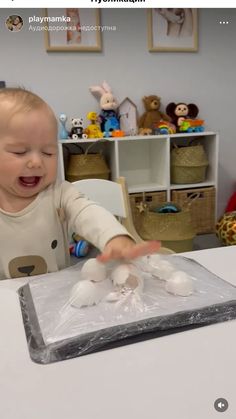 a baby sitting at a table in front of a cake with marshmallows on it