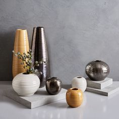 four vases are lined up on top of each other, one is silver and the other is white