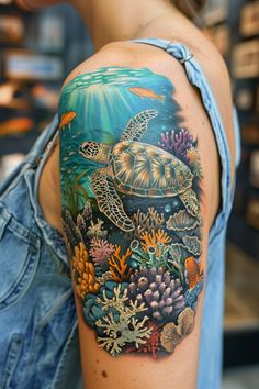 a woman's arm with a turtle and corals tattoo on her left shoulder