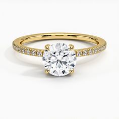 a yellow gold engagement ring with a round cut diamond in the center and pave set shoulders