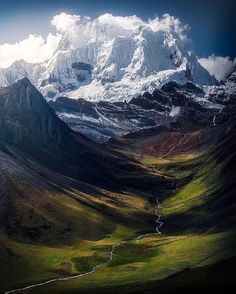 the mountains are covered in snow and green grass, with a stream running between them