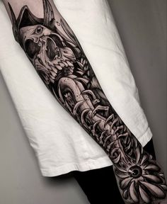 a man's arm with an intricate black and white tattoo design on the forearm