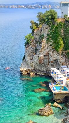 an aerial view of a beach with people swimming in the clear blue water and cliffs