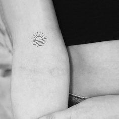 a woman's arm with a small sun tattoo on the left side of her right arm