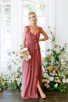 a woman standing in front of flowers wearing a dress