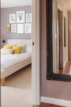 a bedroom with a bed, mirror and pictures on the wall in front of it