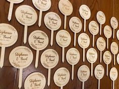 many wooden spoons with names on them are lined up against a wood table top