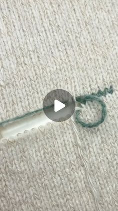 a video demonstrating how to use a crochet hook on a white rug with green yarn