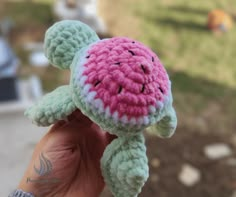 a small crocheted turtle is held in someone's hand