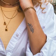 a close up of a person wearing a white shirt with a tattoo on her arm