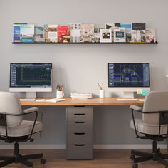 two computer monitors sitting on top of a desk next to each other in an office