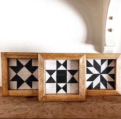 three wooden frames with black and white geometric designs on them, sitting on a table